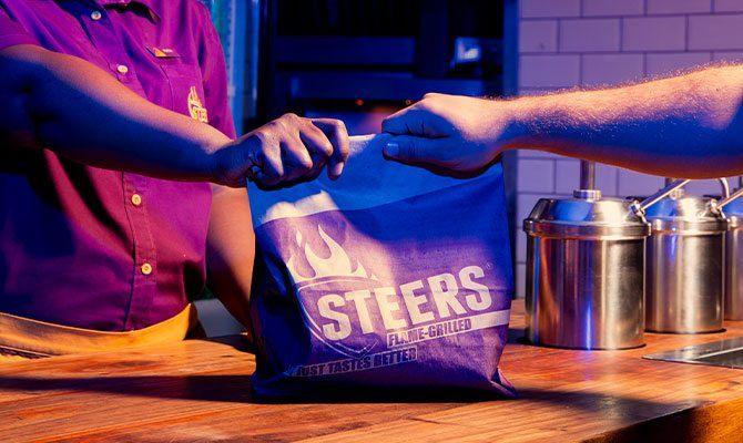 Cashier handing off a takeaway parcel to a customer