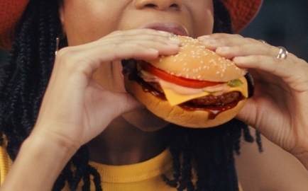 Person taking a bite out of a beef cheese burger