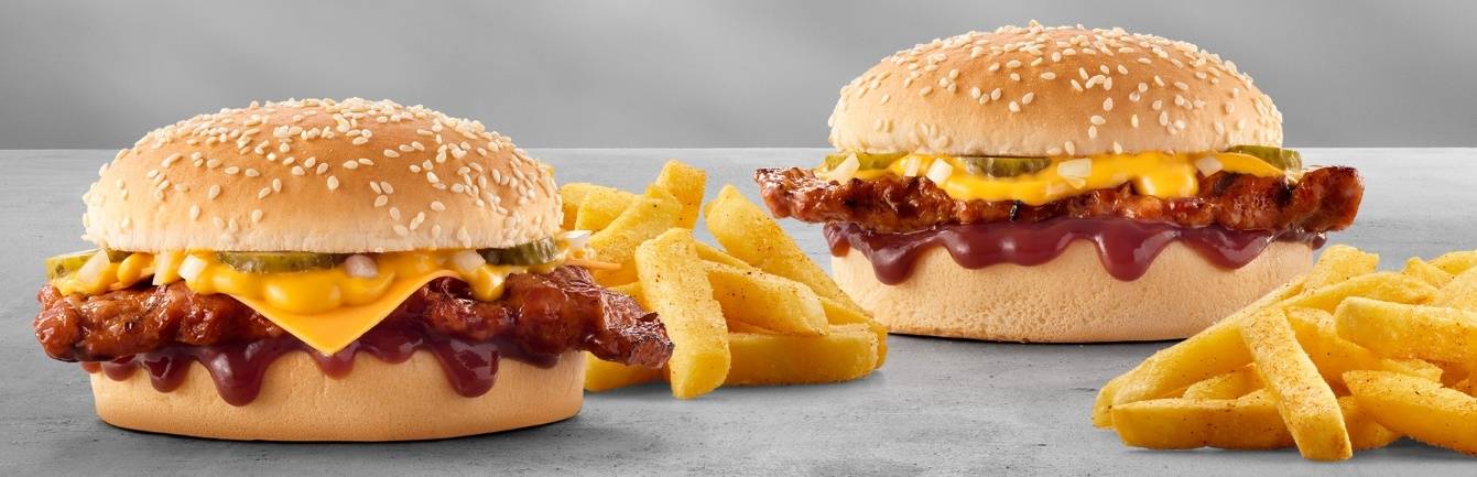 Two ribster burgers with melted cheese sauce, pickles, sesame seed buns, barbecue sauce, with chips