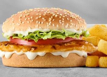 Grilled chicken burger with lettuce, tomato, creamy mayonnaise sauce, sesame seed bun, and crispy chips