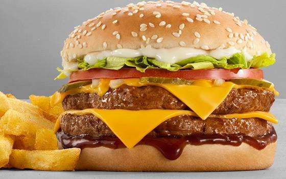 Double beef cheeseburger with melted cheddar cheese, lettuce, tomato, pickles, creamy mayo sauce, sesame seed bun, barbecue sauce, and chips