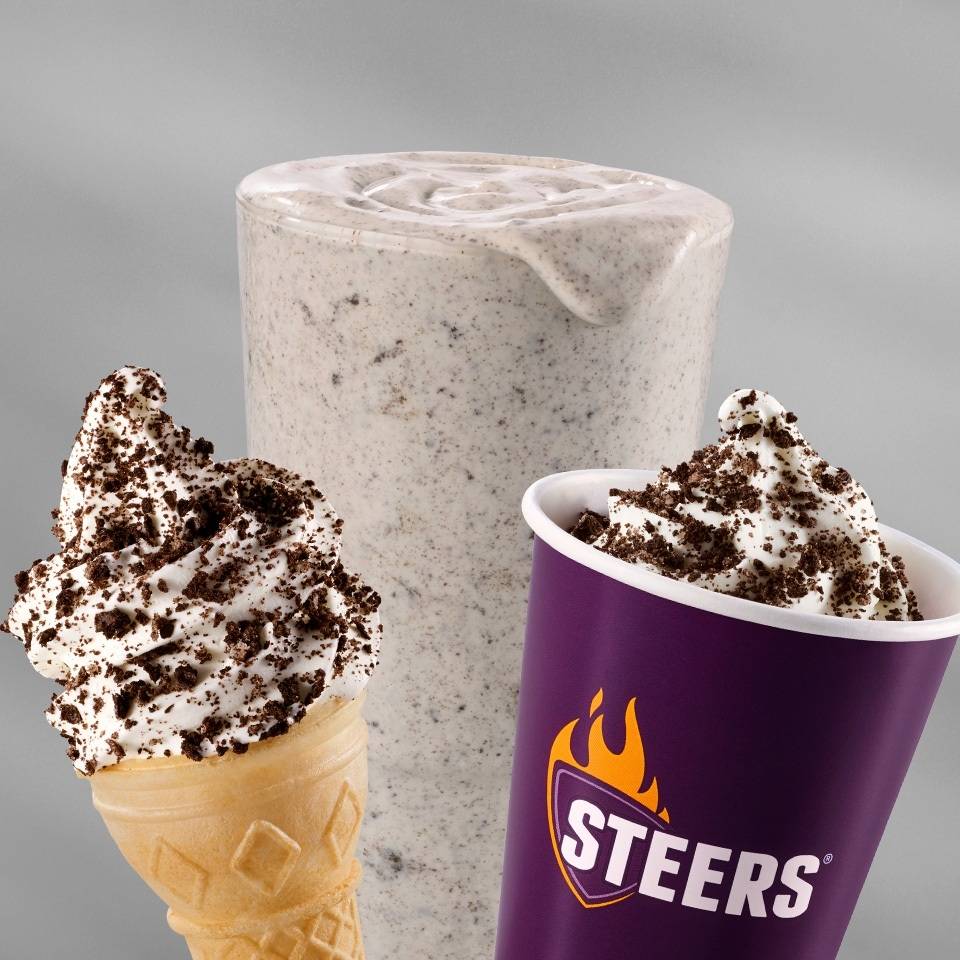 Cookies and cream milkshake with whipped cream, chocolate cookie crumble, soft serve ice cream cone, and branded dessert cup