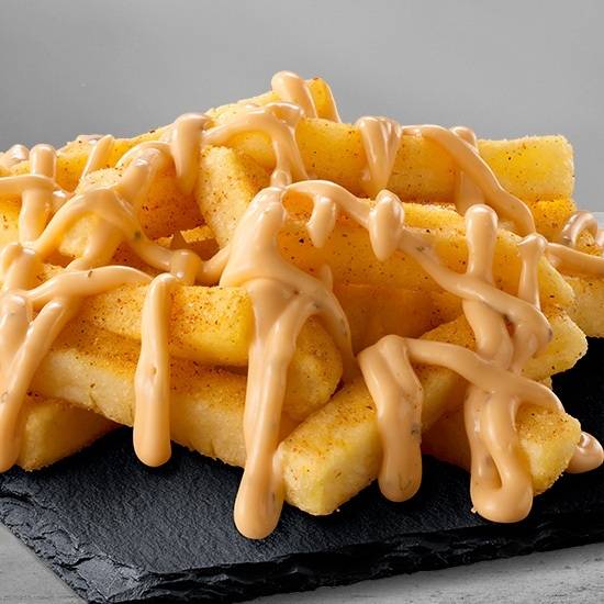 Seasoned chips topped with creamy cheese sauce on a black slate tray