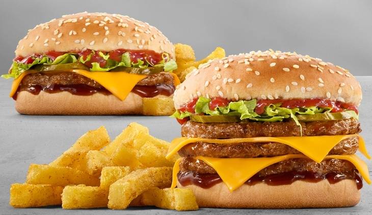 Two stacked cheeseburgers with melted cheddar cheese, lettuce, pickles and barbecue sauce served with chips